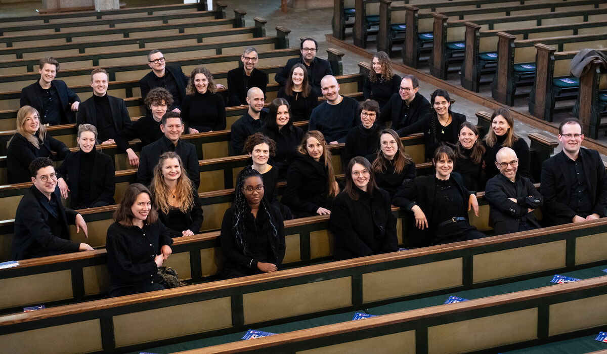 Gemischter Chor verteilt in einem Kirchenraum sitzend